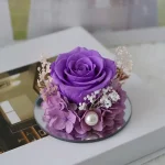 Detail fialové růže, hortenzie, gypsofily a perly uvnitř skleněného andělíčka